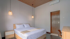 Un dormitorio con cama de madera, mesitas de noche, una puerta de madera y una pequeña mesa con una silla.