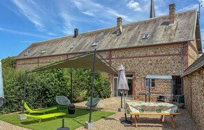 Ein Haus mit überdachter Terrasse, Sitzgelegenheiten im Freien und einer Stein-Fassade.