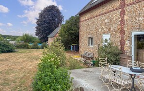 Ein Steinhaus mit Garten, Sitzgelegenheiten im Freien und einem großen Baum.