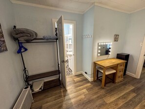 Ein Zimmer mit einem Etagenbett, einem Schminktisch mit Spiegel und Beleuchtung, einem Holztisch und einem Heizkörper.