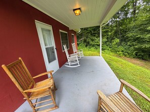 A covered porch with two rocking chairs and a concrete floor. - The Honey Bear Retreat nestled in the heart of Maggie Valley (Maggie Valley)
