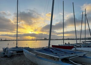 Ein Hafen mit vertäuten Booten, im Hintergrund ein Sonnenuntergang und ruhiges Wasser.