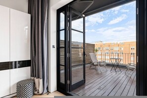 Ein Balkon mit Blick auf ein Backsteingebäude, ein Stuhl und ein kleiner Tisch.