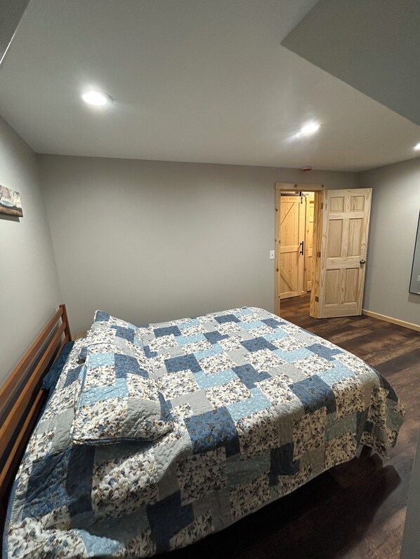 A bedroom with a bed, a wooden door, and a light switch on the wall.
