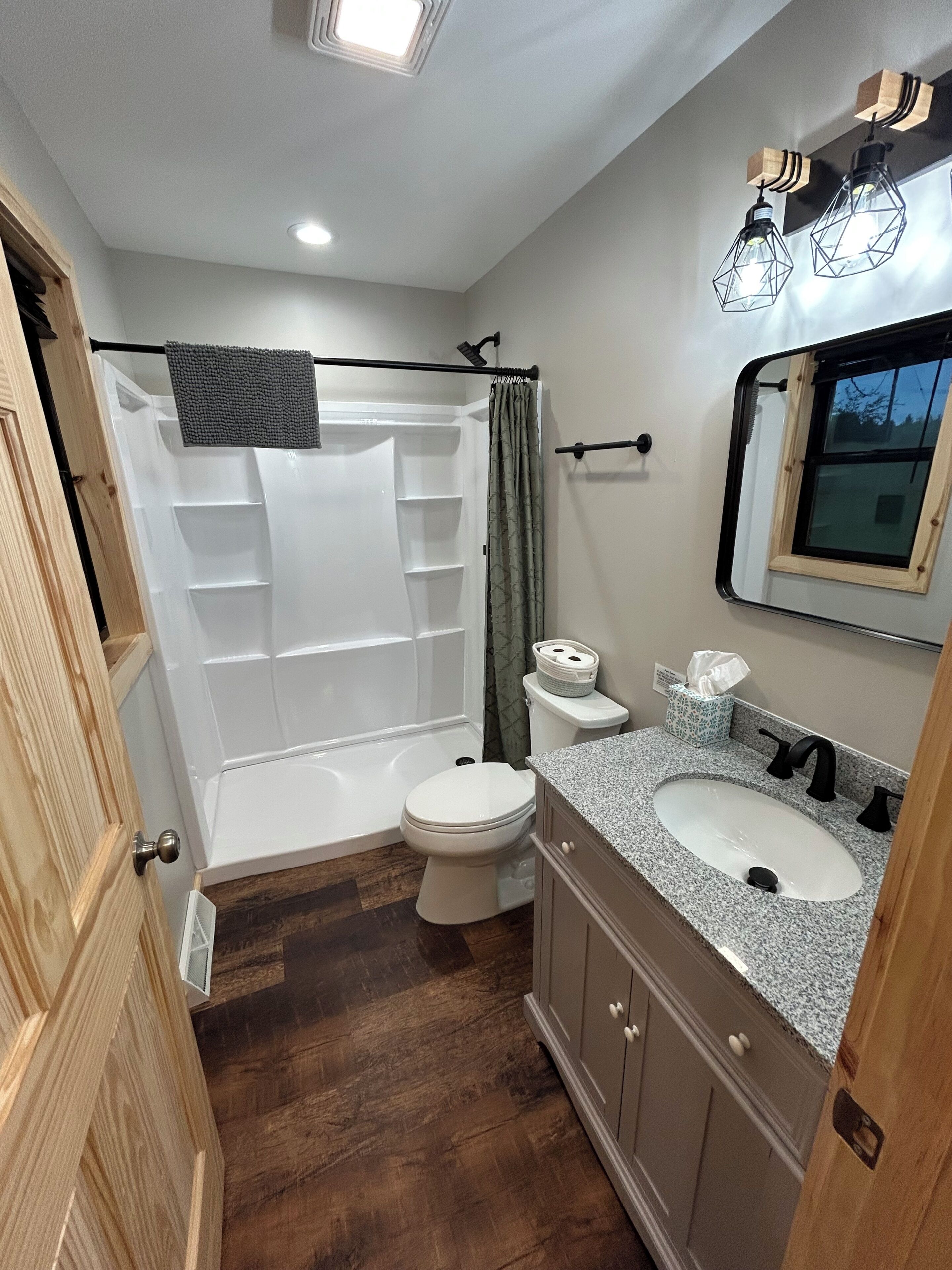 A bathroom with a shower, toilet, sink, and vanity.