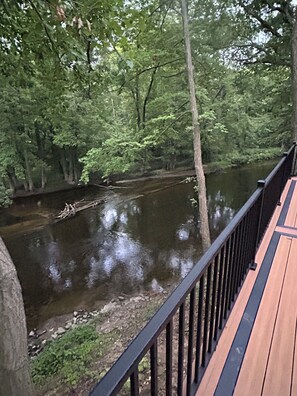 A wooden deck overlooking a calm river with dense foliage in the background.