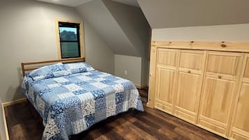 A bedroom with a bed, wooden wardrobe, and a window.