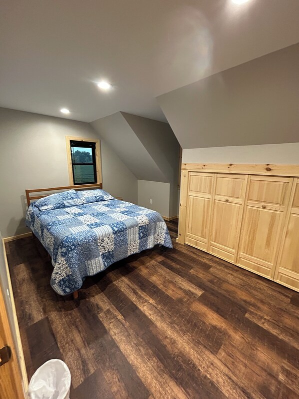 A bedroom with a bed, wooden wardrobe, and a window.