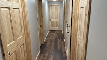 A hallway with wooden doors on both sides, a dark wooden floor, and a ceiling light.
