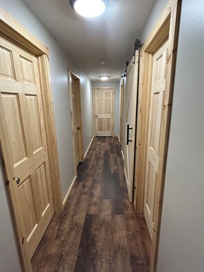 A hallway with wooden doors on both sides, a dark wooden floor, and a ceiling light.