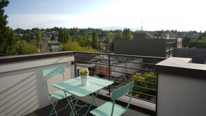 A balcony with a table and chairs, a potted plant, and a cityscape view in the background. - Timeless 3BR Retreat Central Fremont (Seattle)