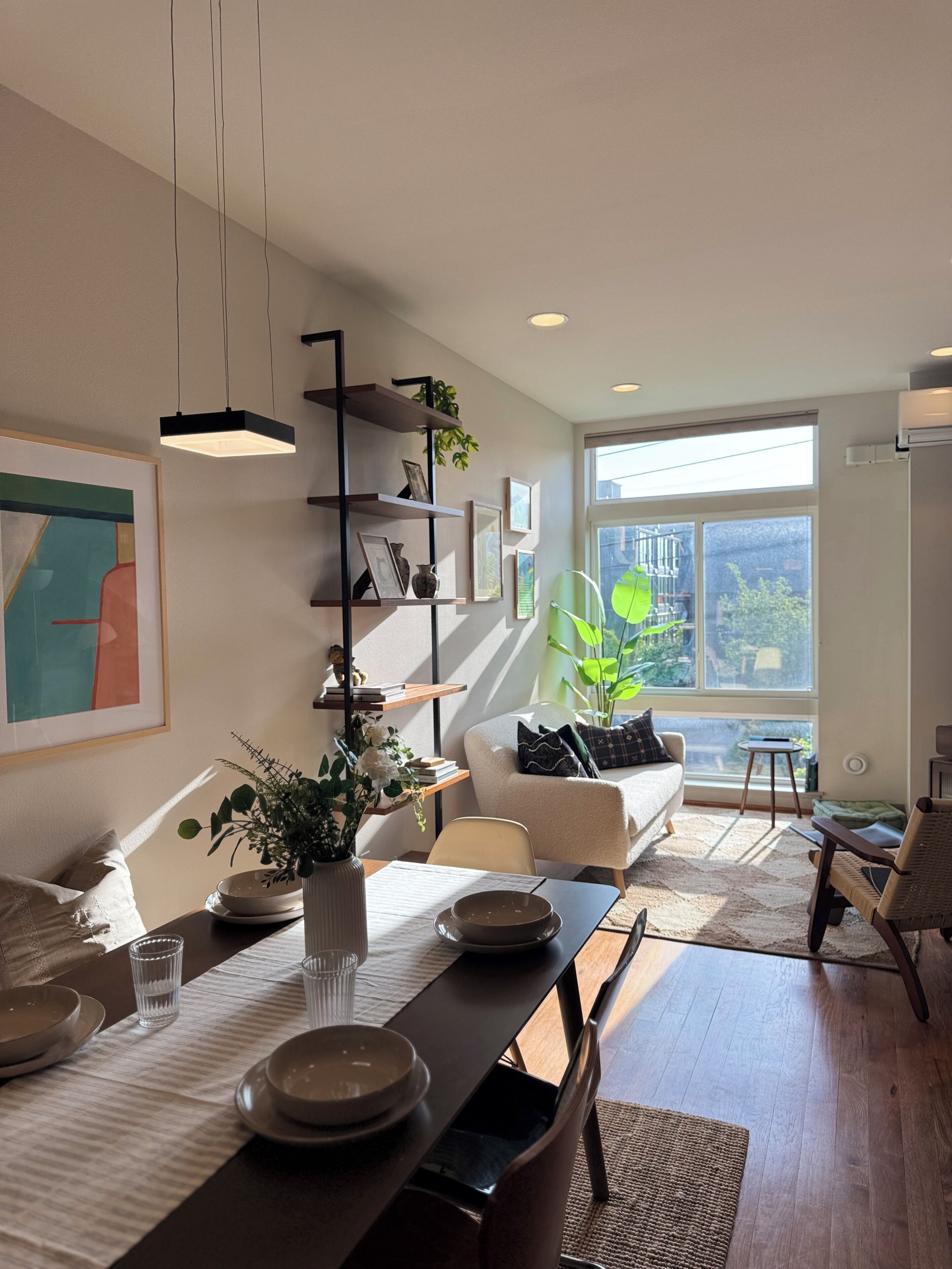 A modern living room with a dining area, featuring a sofa, a coffee table, and a bookshelf.