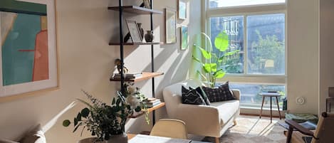 A modern living room with a dining area, featuring a sofa, a coffee table, and a bookshelf.