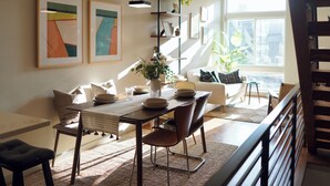 Uma área de refeições com mesa posta para quatro pessoas, um sofá e uma escada.