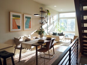 A dining area with a table set for four, a sofa, and a staircase. - Timeless 3BR Retreat Central Fremont (Seattle)