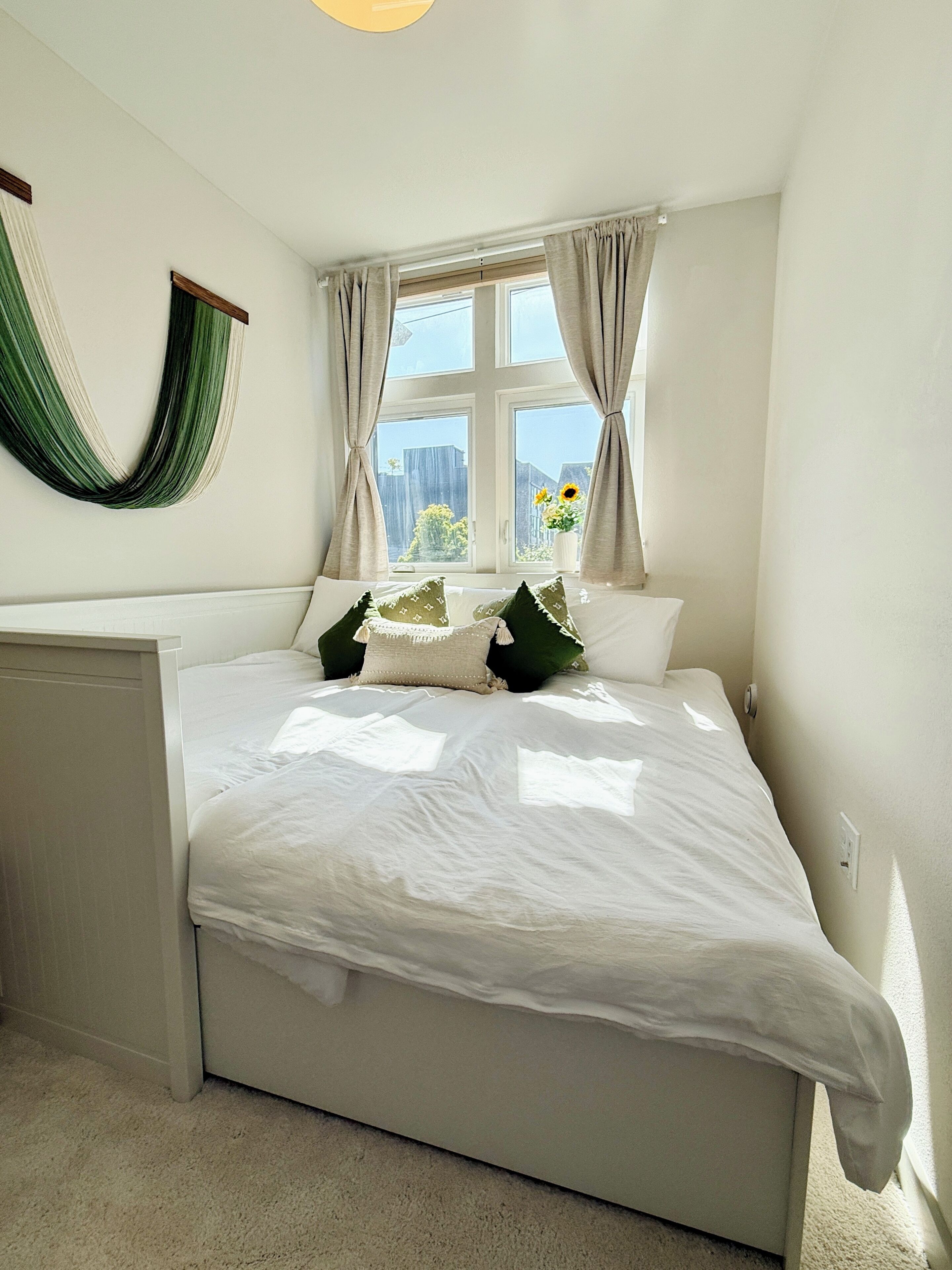 Un dormitorio con una cama grande, una ventana con cortinas, una hamaca en la pared y vistas al exterior.