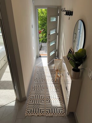 A hallway with a patterned rug, a door leading outside, a mirror, and a potted plant. - Timeless 3BR Retreat Central Fremont (Seattle)