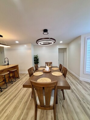 Un comedor con una mesa de madera, seis sillas y una lámpara colgante moderna.