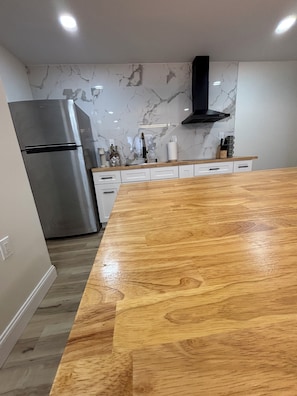 Cocina moderna con refrigerador de acero inoxidable, encimera de madera y salpicadero de mármol.