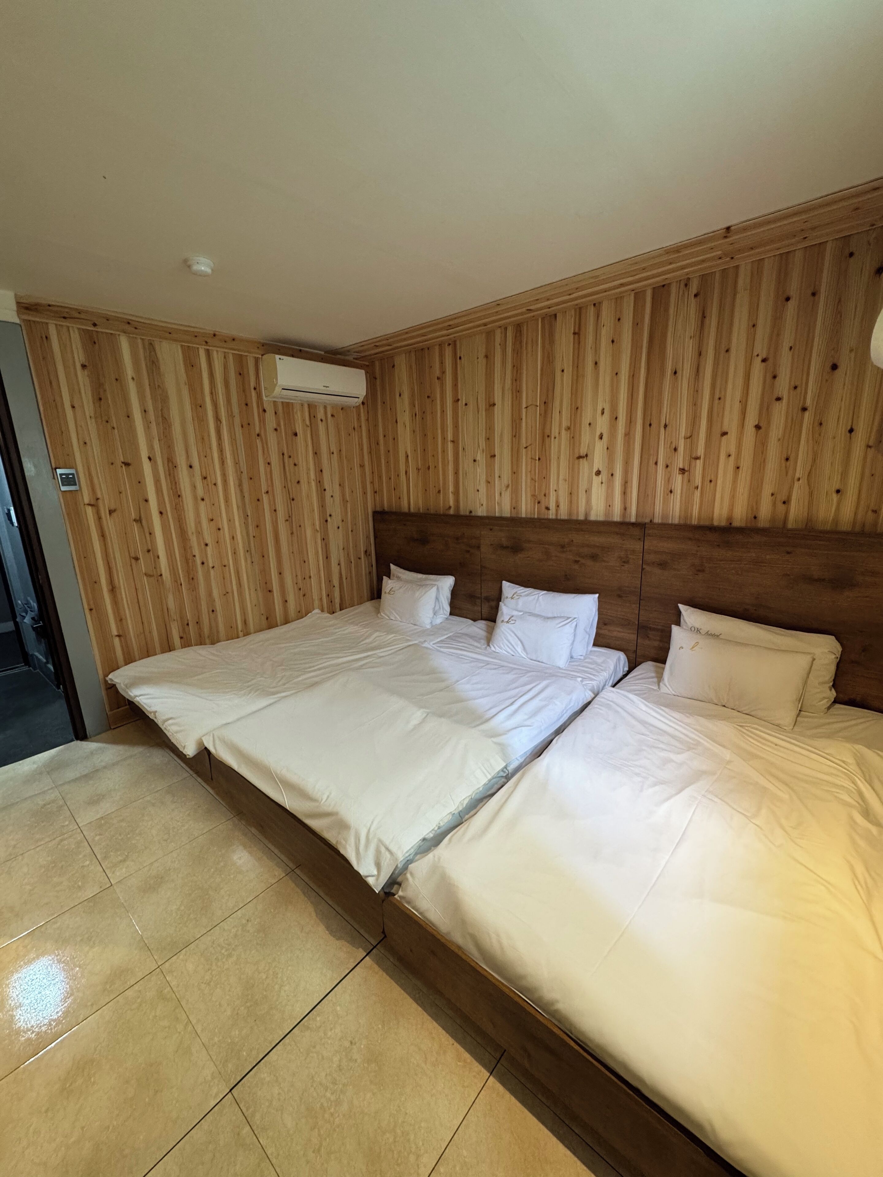 A double bed with a wooden headboard in a room with wooden paneling on the walls.