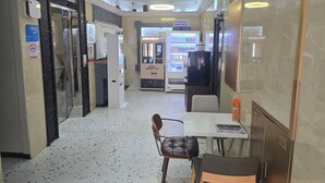 A hotel lobby with a reception desk, a minibar, a refrigerator, and a vending machine.