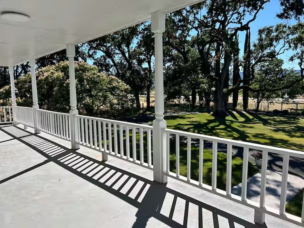 A covered outdoor area with white railings and a paved floor.