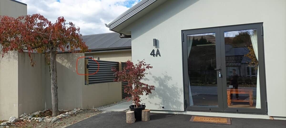 A building with a large glass door, a number '4A' on the wall, and a small tree with red leaves.