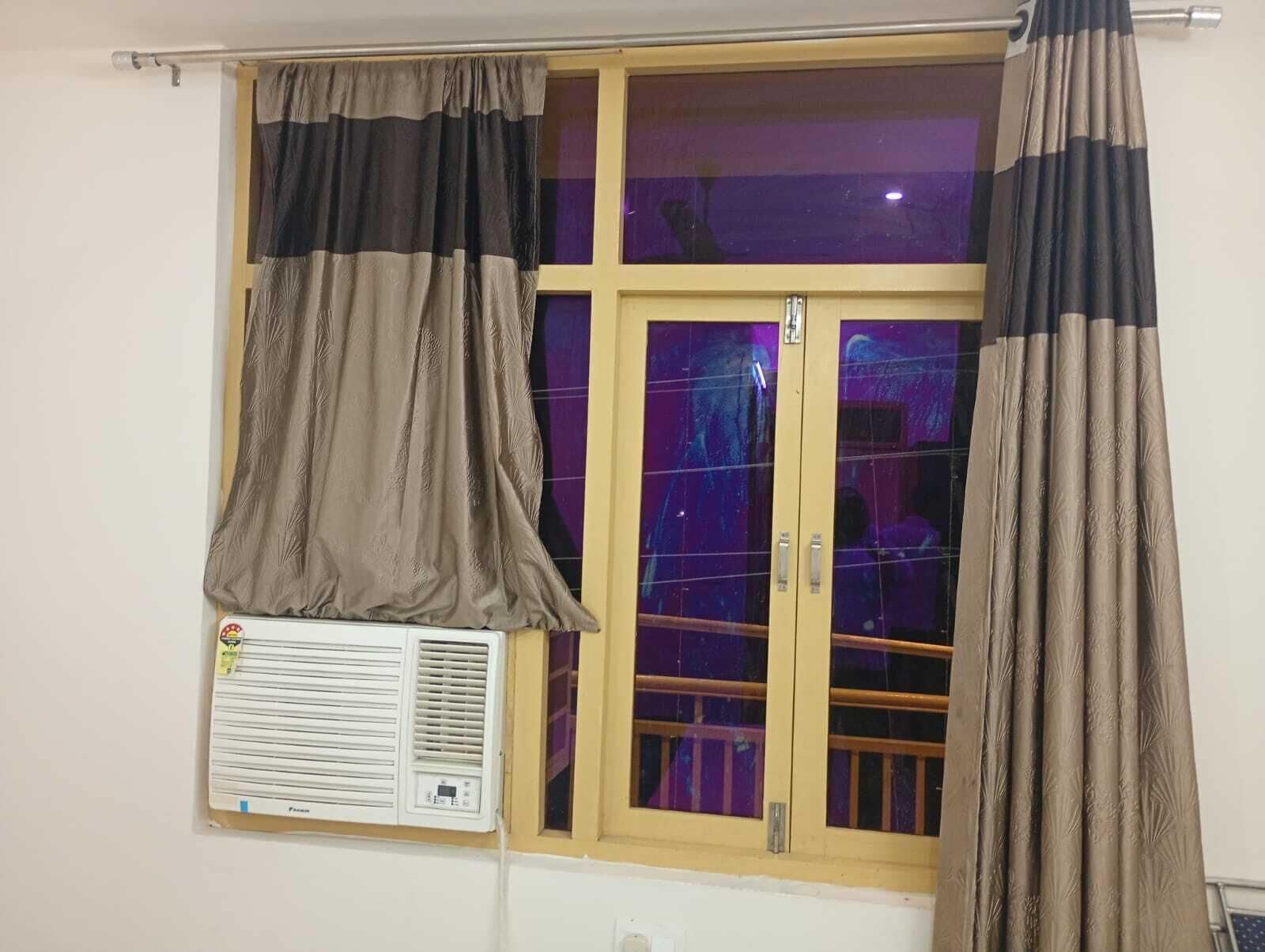 Una habitación con ventana, aire acondicionado y cortinas.