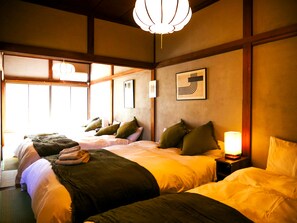 Habitación de hotel con dos camas, un ventanal grande y una lámpara colgante.
