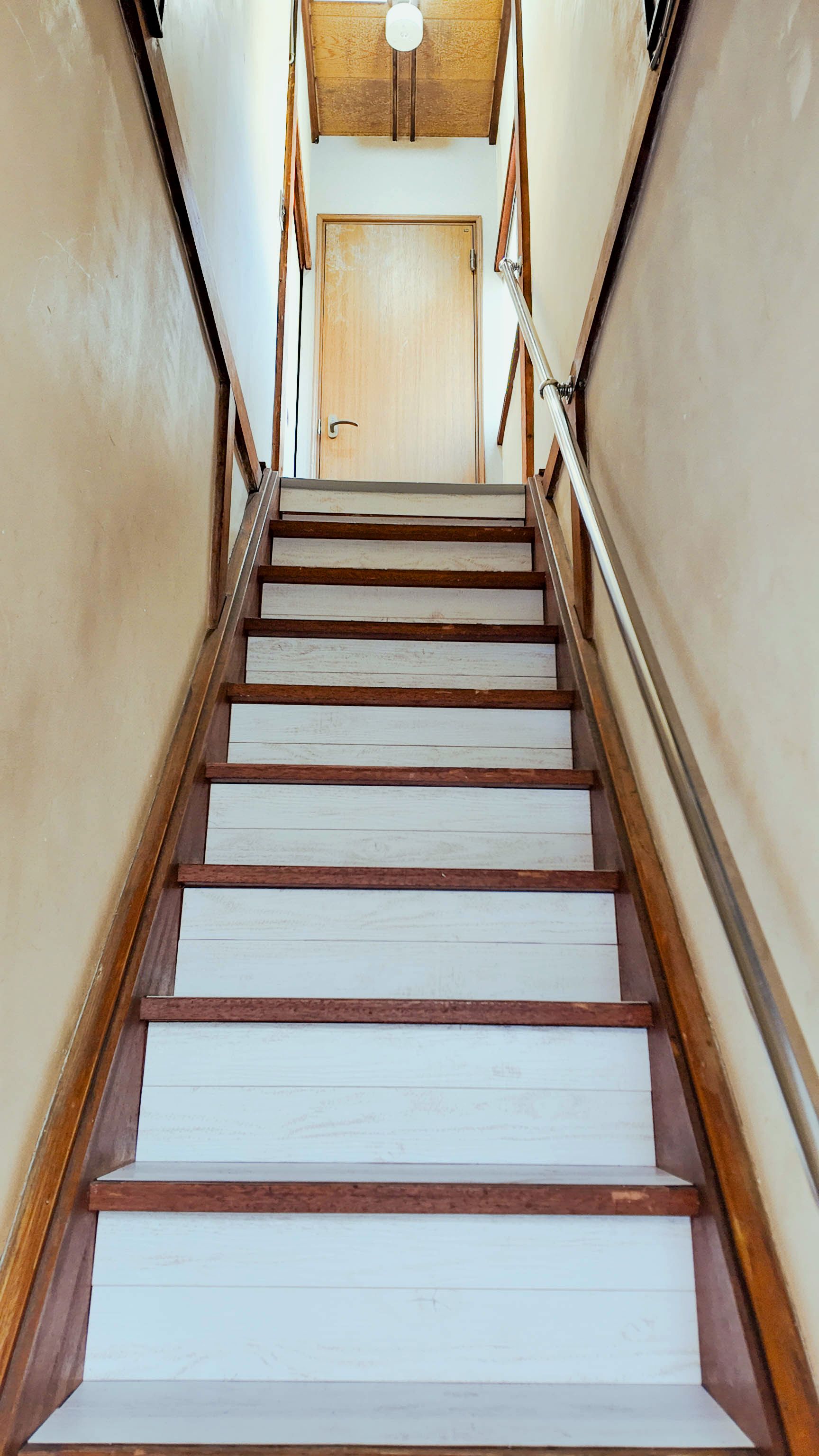 A staircase with wooden steps and metal railings leading to a door at the top.