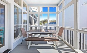 A covered outdoor area with a table and chairs, large windows, and a view of buildings. - My Blue Sky - Fire Pit, Neighborhood Beach Access! (Santa Rosa Beach)