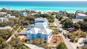 A coastal residential area with houses, a large building with a distinctive roof, and a clear view of the ocean. - My Blue Sky - Fire Pit, Neighborhood Beach Access! (Santa Rosa Beach)