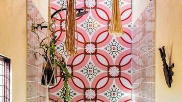 A bathroom with patterned tiles, a hanging plant, and a decorative ceiling light fixture.