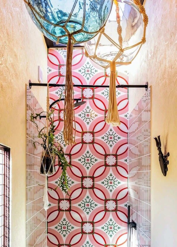 A bathroom with patterned tiles, a hanging plant, and a decorative ceiling light fixture.