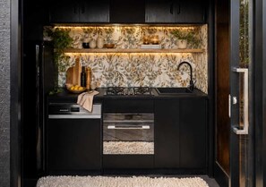 A compact kitchen with a built-in stove, a sink, and a countertop with a towel. There are cabinets and a window above the sink.