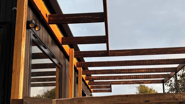 Een houten terras met een bar, inclusief een tafel en stoelen.