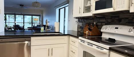 A modern kitchen with white cabinetry, a built-in oven, microwave, and dishwasher.