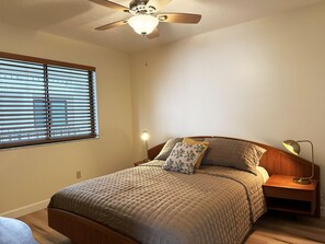 A bedroom with a bed, a nightstand, a lamp, a ceiling fan, and a window with blinds. - Sandpiper Key 2BR Bay Views & Heated Pools (Englewood)