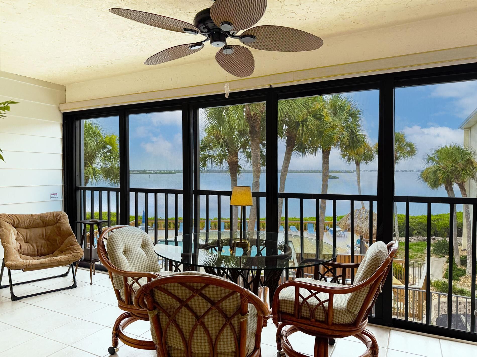 Ein Balkon mit Meerblick, ausgestattet mit Korbstühlen und einem Tisch, sowie einem Deckenventilator.