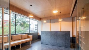 A modern interior with a bench, a reception desk, and large windows. - Myla - 2 - Magnolia Centro Historico (Mexico City)