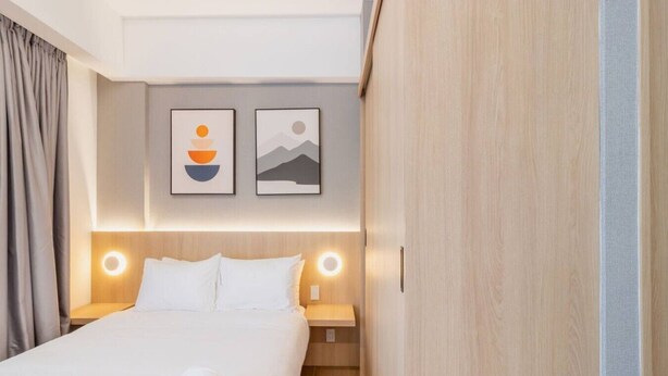 A hotel room with a bed, two bedside tables, a headboard with integrated lighting, and two wall-mounted artworks. - Myla - 2 - Magnolia Centro Historico (Mexico City)