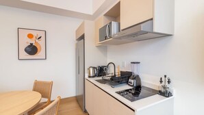 A compact kitchen with a stove, kettle, and blender, a dining area with a table and chairs, and a microwave above the counter. - Myla - 2 - Magnolia Centro Historico (Mexico City)