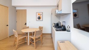 A compact living space with a dining table, chairs, a kitchenette, and a door. - Myla - 2 - Magnolia Centro Historico (Mexico City)