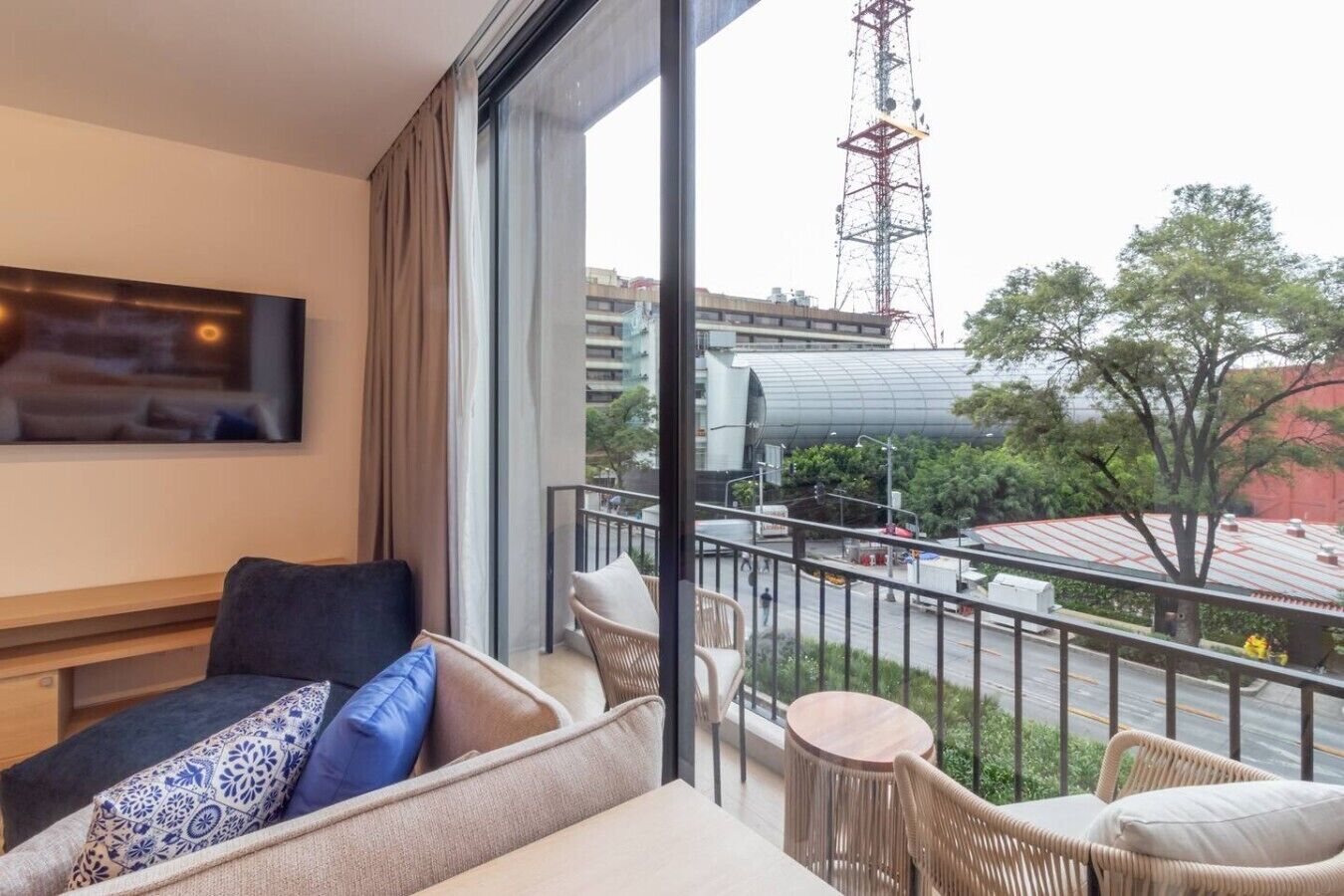 Habitació d'hotel amb un balcó, un sofà, una taula petita i vista a la ciutat.