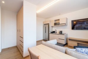 Un espace de vie moderne et compact comprenant un coin cuisine, un coin repas et un canapé.