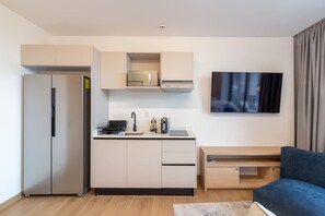 A compact living space with a kitchenette, a flat-screen TV, and a sofa. - Myla - 3 - Magnolia Centro Historico (Mexico City)