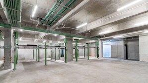 Sisätiloissa sijaitseva pysäköintihalli, jossa on betonilattiat ja vihreät, rakenteelliset tukipilarit.