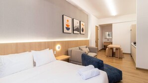 Une chambre d’hôtel avec un grand lit, un canapé, un bureau et une kitchenette.