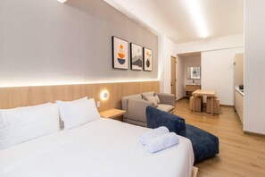 Ein Hotelzimmer mit einem großen Bett, einer Sitzecke, einem Schreibtisch und einer Küchenzeile.