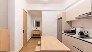 Une cuisine de taille réduite, avec une table en bois, un évier, un réfrigérateur et une cuisinière.